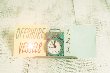 Conceptual hand writing showing Offshore Vessels. Concept meaning ship designed to supply offshore oil and gas platforms Mini blue clock standing above buffer wire between two paper