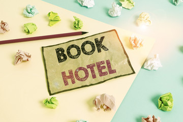 Handwriting text writing Book Hotel. Conceptual photo an arrangement you make to have a hotel room or accommodation Colored crumpled papers empty reminder blue yellow background clothespin