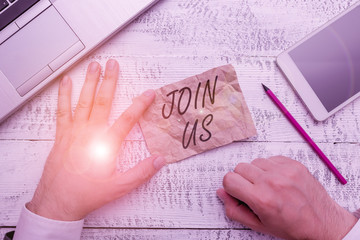 Writing note showing Join Us. Business concept for Register in community Team or blog Sign up at social media Hand hold note paper near writing equipment and smartphone