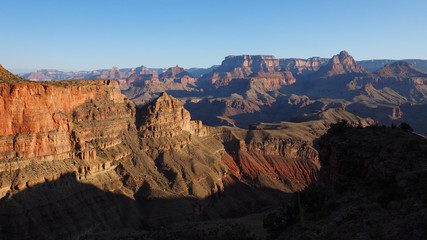 Early morning view from New Hance Trail in Grand Canyon National Park, Arizona under clear blue sky.