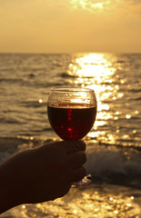 glass of red wine in his hand. Romantic day by the sea at sunset. The concept of wedding or Valentine Day celebrations.