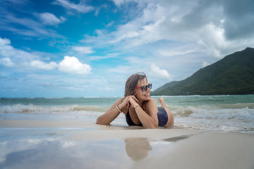 Young beautiful lies in the sand on a tropical paradise beach laughs, enjoys life, travel and vacation on the tropical ocean