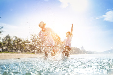 Happy father jumping together with son on the beach. Father and son play on the beach on summer...