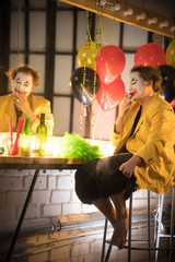Clown concept - a sad tired man clown in yellow jacket smoking in the dressing room and thinking...