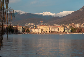 the city of Lugano overlooking the lake in the canton of Ticino, surrounded by snow-covered mountains.Switzerland