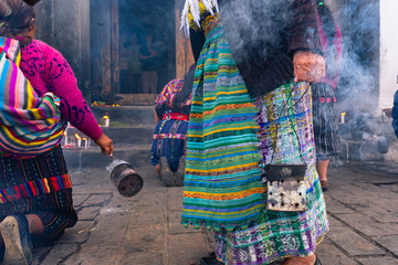 Las personas mayas están echando  incienso y encendiendo velas en la entrada de la Iglesia de...