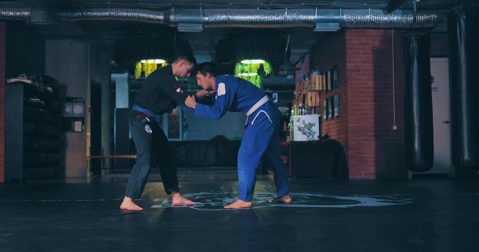 Man holds a fighter in capturing the enemy, throwing a coup, applying a pain technique. Jujitsu fighters train the technique of fighting.