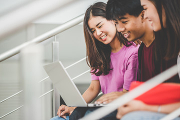 Education concept - Happy young university students enjoy using laptops on campus.