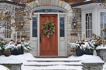 Front door of snow covered house with Christmas wreath - Powered by Adobe
