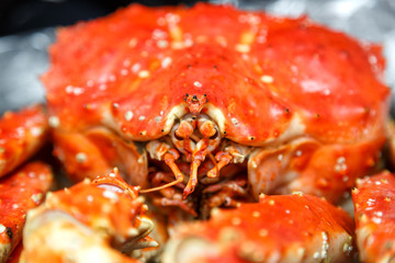 Baked Kamchatka crab whole on a black plate.