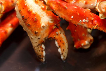 Claws baked Kamchatka crab whole on a black plate.