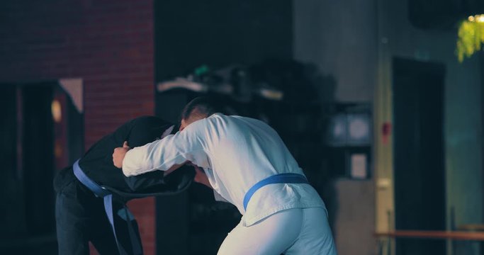 Judo athletes train painful techniques on the floor, training fighters in a kimono. Gym for wrestling.