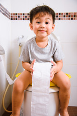 Asian little  kid 2-3 years old sitting on a kid bathroom accessory toilet