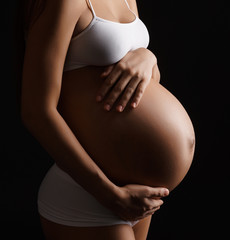 Pregnant young woman posing in lingerie in studio