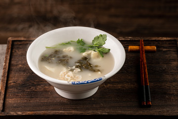 Shrimp wonton with braised pork in soup on wooden table / Select focus image...