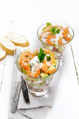Salad with shrimp and avocado in two glasses on board