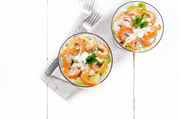 Salad with shrimp and avocado in two glasses on table top