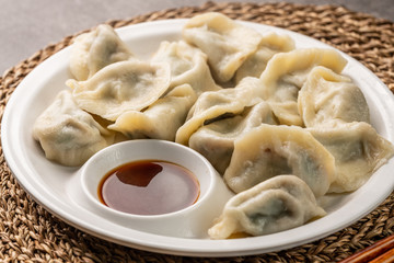 Close up fresh boiled dumplings with hot steams on wood plate. Chinese food on rustic old vintage wooden background.
