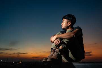 black Asian man and bearded on face with cool haircut wear tactical suit and hard brown boots makes depress face looking for future and redemption in beautiful evening twilight time photo stock