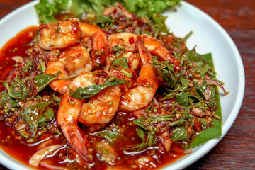 Spicy Neem Tree flower with prawns salad on a white plate on a wooden table