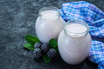 Blackberry yogurt in a jar on a black background. Copy space.