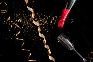 New year and christmas holidays background. Golden spirals ribbon and sparkles on black background.