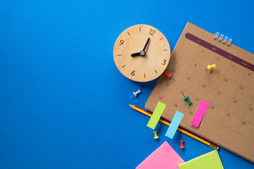 close up of calendar and alarm clock on the blue table background, planning for business meeting or travel planning concept © tatomm