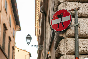 Traffic signs with little people painted on them on the streets of Rome, Italy.