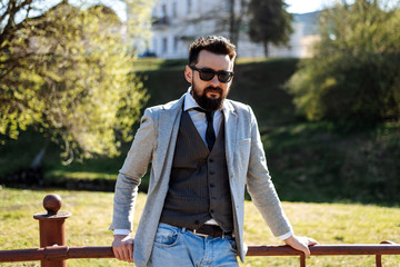 Fototapeta premium Young successful handsome man in a gray jacket is standing on the street