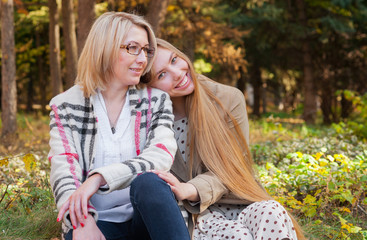 Friendly relations of an adult daughter and mother. Happy family, young woman hugs her mom in  park