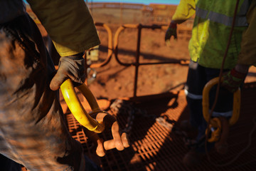 Defocused of construction male rigger hands wearing a heavy duty safety protection glove while holding lifting dragging crane hook on open field construction site   