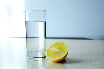 a glass of water and lemon stands on the table.