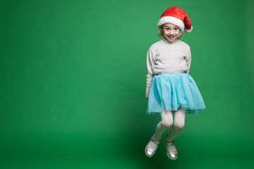 Happy little girl in Santa Claus hat jumping