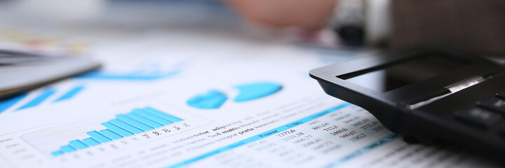 Black calculator and financial statistics on clipboard pad