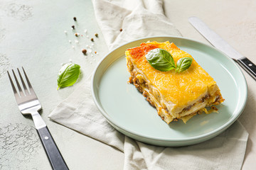 Plate with tasty baked lasagna and ingredients on light background