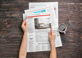 Woman reading newspapers at wooden table