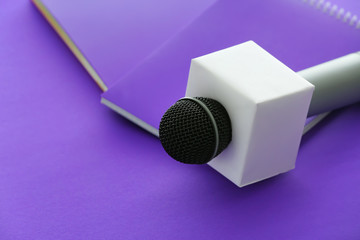 Journalist's microphone and notebooks on color background