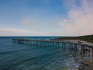 Fototapeta na wymiar A long jetty on the coastline with blue sunny sky.