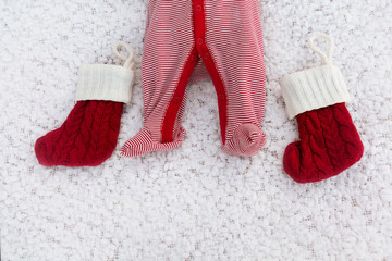 Newborn legs with Christmas socks on a white blanket as a background