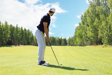 Full length of golf player playing golf on sunny day. Professional male golfer taking shot on golf...