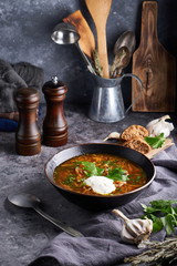 Traditional European and Russian soup borsch with cabbage, sour cream and meat served in a plate on a dark stone table Vertical