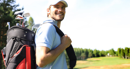 Golf player walking and carrying bag on course during summer game golfing.