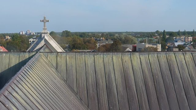 Panning shot through window glass of Christian church roof with cross in a Baltic seaside town Palanga, Lithuania.