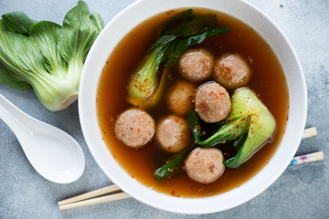 White bowl with meatballs and  bok choy in miso broth, view from above, close-up