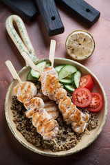 Fried chicken skewers, quinoa and fresh vegetables in a serving pan, studio shot, elevated view