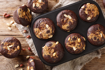 delicious breakfast of chocolate muffins with peanut butter and nuts in a baking dish. Horizontal...