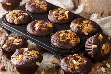 Freshly baked chocolate muffins with peanut butter and nuts in a baking dish. horizontal