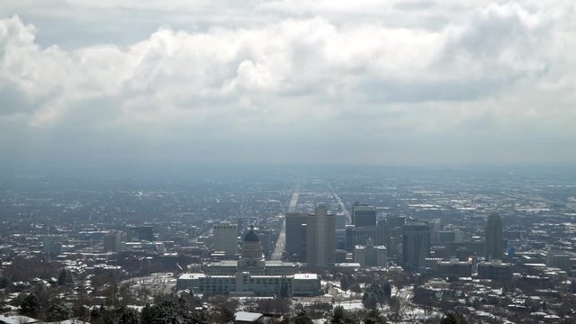 Wide view of Salt Lake City downtown on cloudy day from behind the capitol building on a hill.