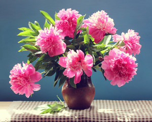bouquet of pink peonies with leaves in a clay jug.