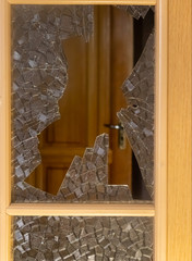 Interior door with broken glass. The concept of family quarrels, domestic violence, fights, rage and anger.